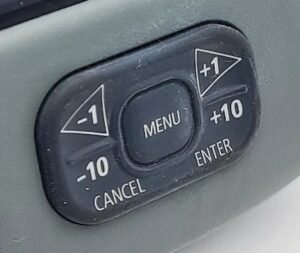 The ST70's rocker. Nothing on it is marked < or > — the manual's scroll keys are the left and right sides of this pad, the same ones labelled -1 and +1. Menu is the centre button, with Cancel and Enter as the lower corners.